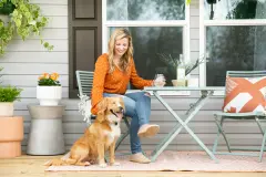 Person sitting with dog on the front porch of their manufactured home.