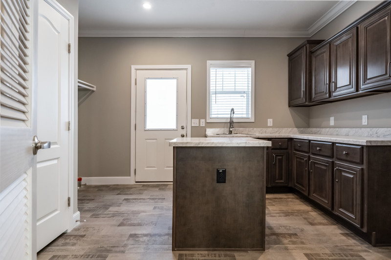 A large laundry room in the Clayton Built® home, The Baylee, that features a lot of cabinet storage and an island.