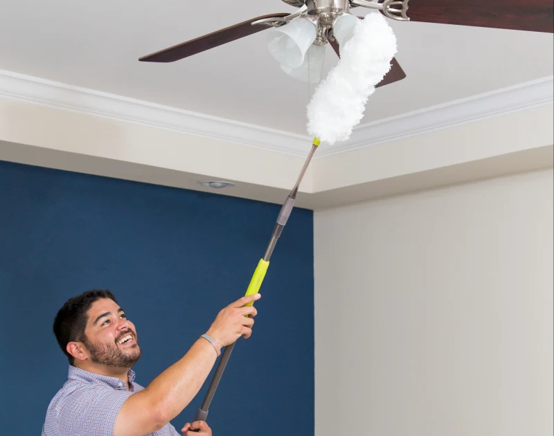 Man dusting a ceiling fan in a manufactured home.