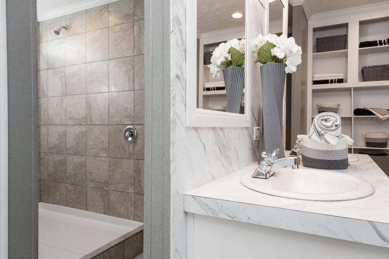 Manufactured home primary bathroom with walk in shower and double vanity