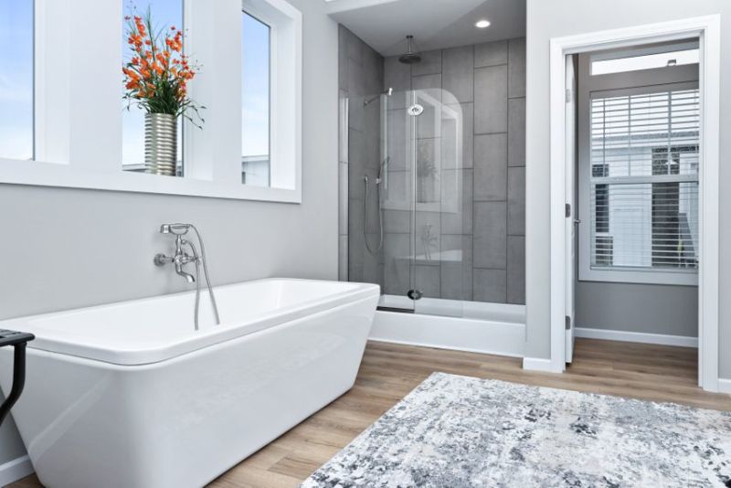 A large bathroom with a separate soaking tub and a walk-in shower with gray tile walls and a glass door.