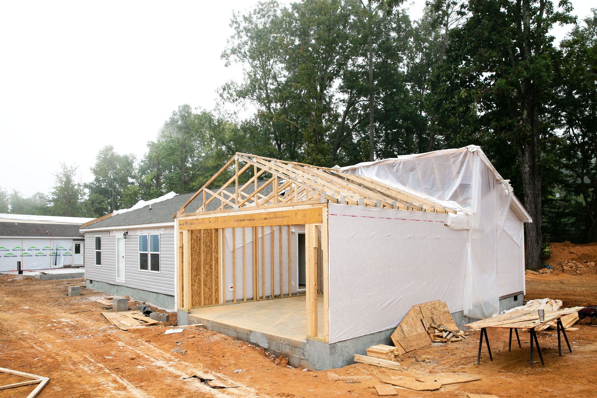 A garage under construction on the side of a manufactured home that has been placed on land