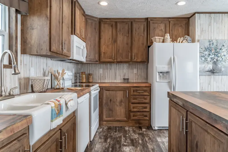 The wooden cabinetry and rustic wallpaper in the kitchen of The Locker Room model by Clayton.