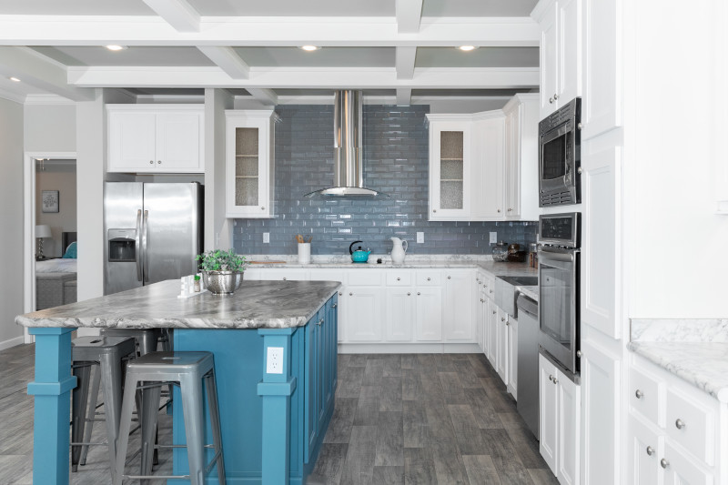 A contemporary style kitchen with a large blue island and subway tile backsplash