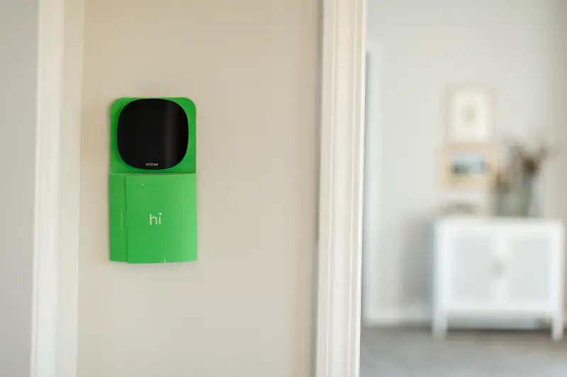 Close-up of an ecobee thermostat on the wall beside a doorway with a green sign on it reading "hi."