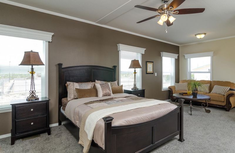 Bed centered in photo with couch in background in a Clayton manufactured home.