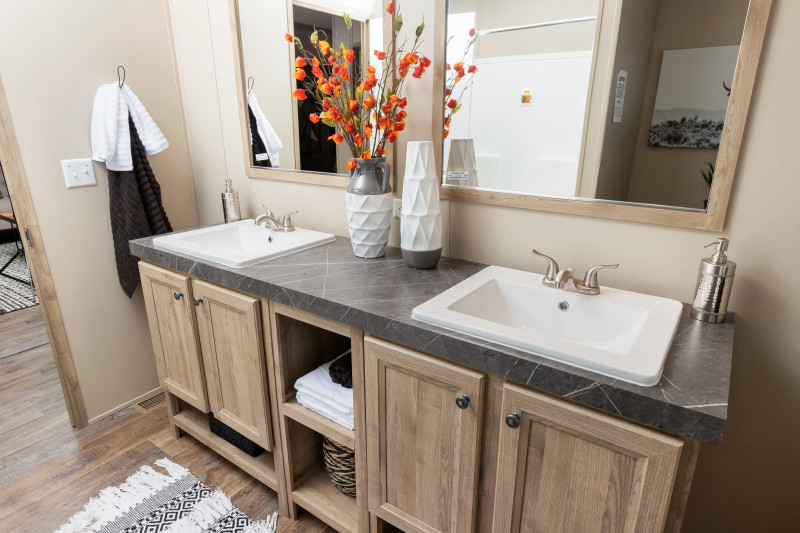 Side view of the guest bathroom with double vanity sinks with two mirrors. Vanity is light-colored wood with gray countertops.