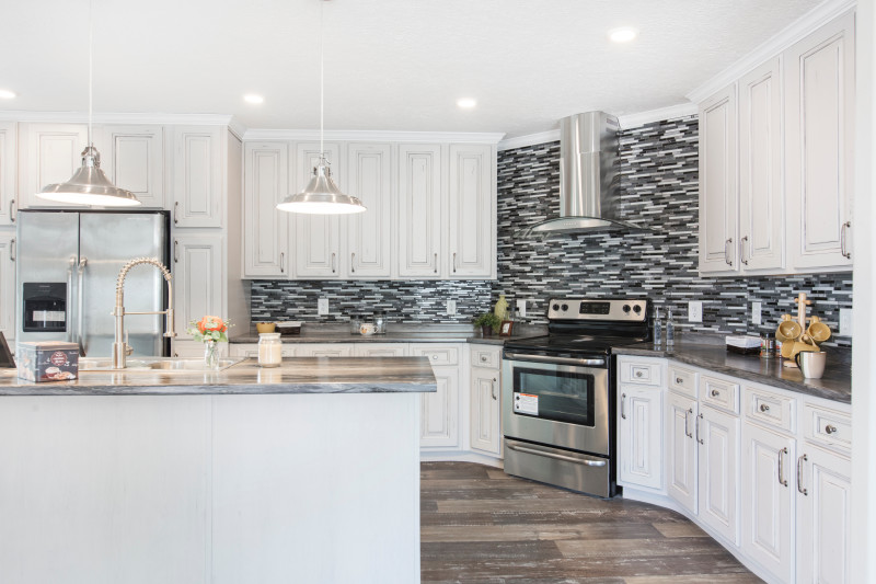 Gorgeous kitchen with white cabinetry, overhead lighting above the island and stylish backsplash.