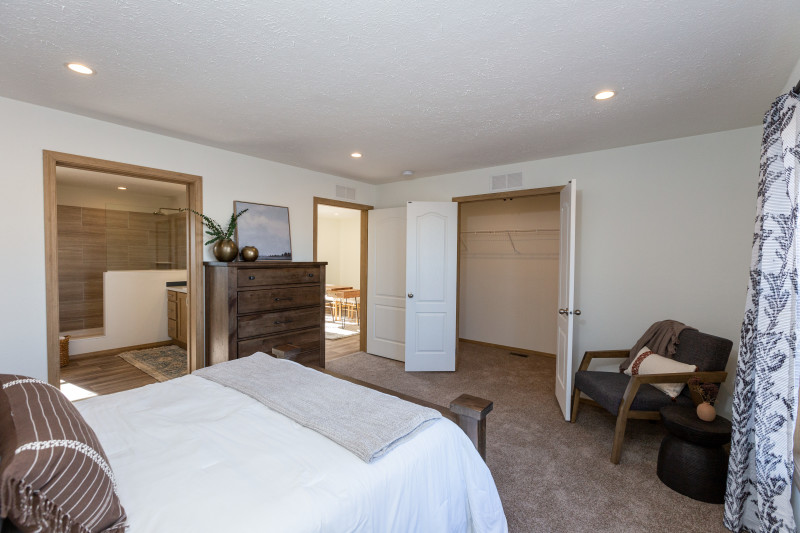 Bed in foreground with doors to bathroom and flex room open in a Clayton manufactured home.