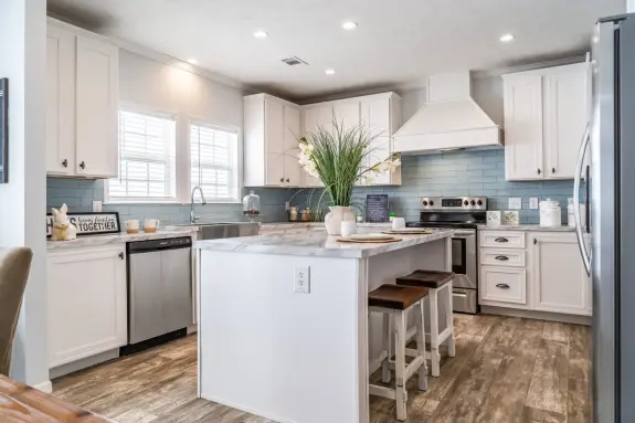 The kitchen of [model name] features subway tile backsplash and marble-style countertops.