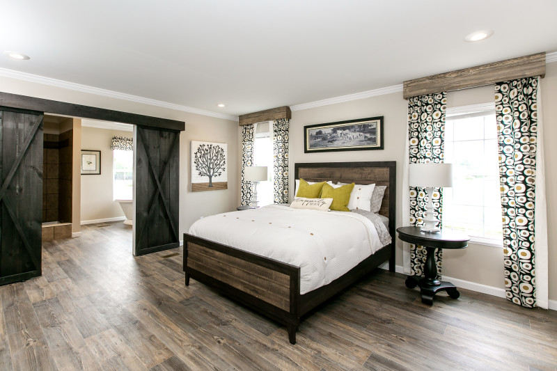 Manufactured home bedroom with wood styled flooring and large barn doors.