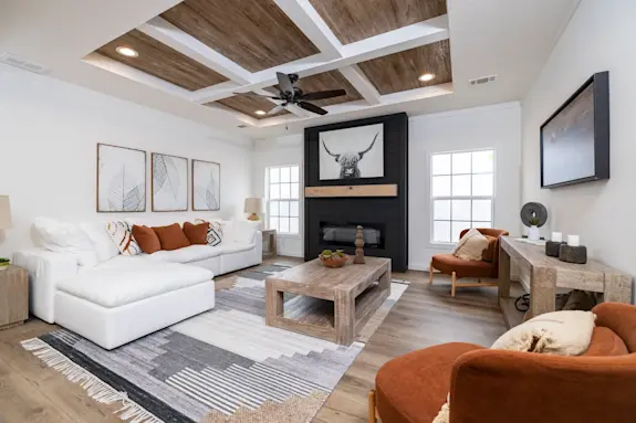 The [model name] features a living room with a coffered ceiling and floor-to-ceiling fireplace.