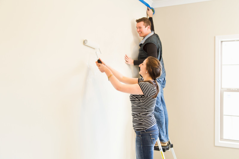 Couple painting a manufactured home wall.