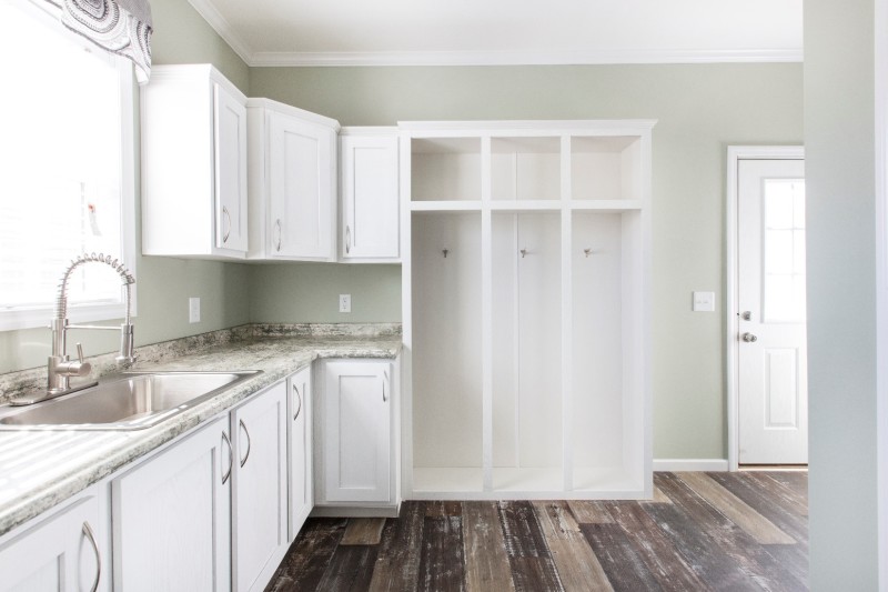 Bright laundry room in a modular home with built-in white cabinets and sink.