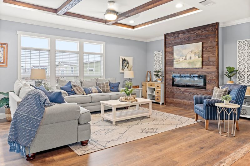 A manufactured home living room with windows, wooden beams, wooden accent wall and fireplace