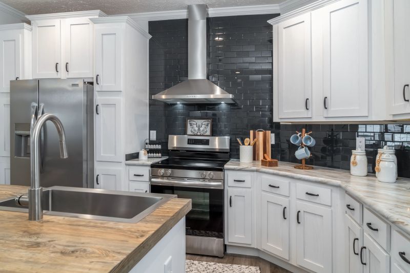 A stainless steel kitchen hood sits above an oven with dark gray, shiny tiling behind it.