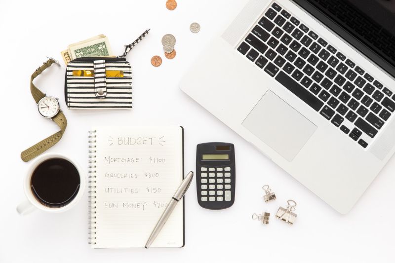 Flat lay of a laptop, notebook with a budget, coffee cup, wallet and office supplies