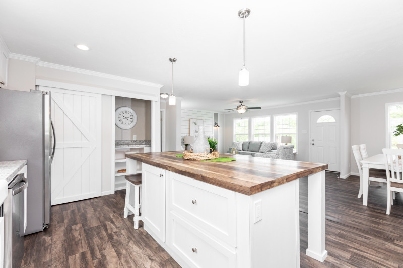 The kitchen of the Island Breeze model featuring sliding white barnwood doors to the pantry.