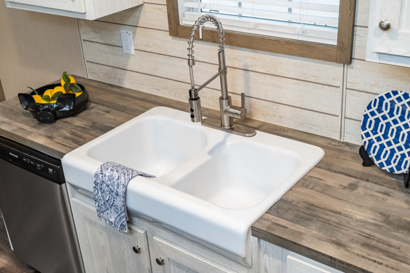 A white farmhouse sink with a gooseneck faucet in a manufactured home.