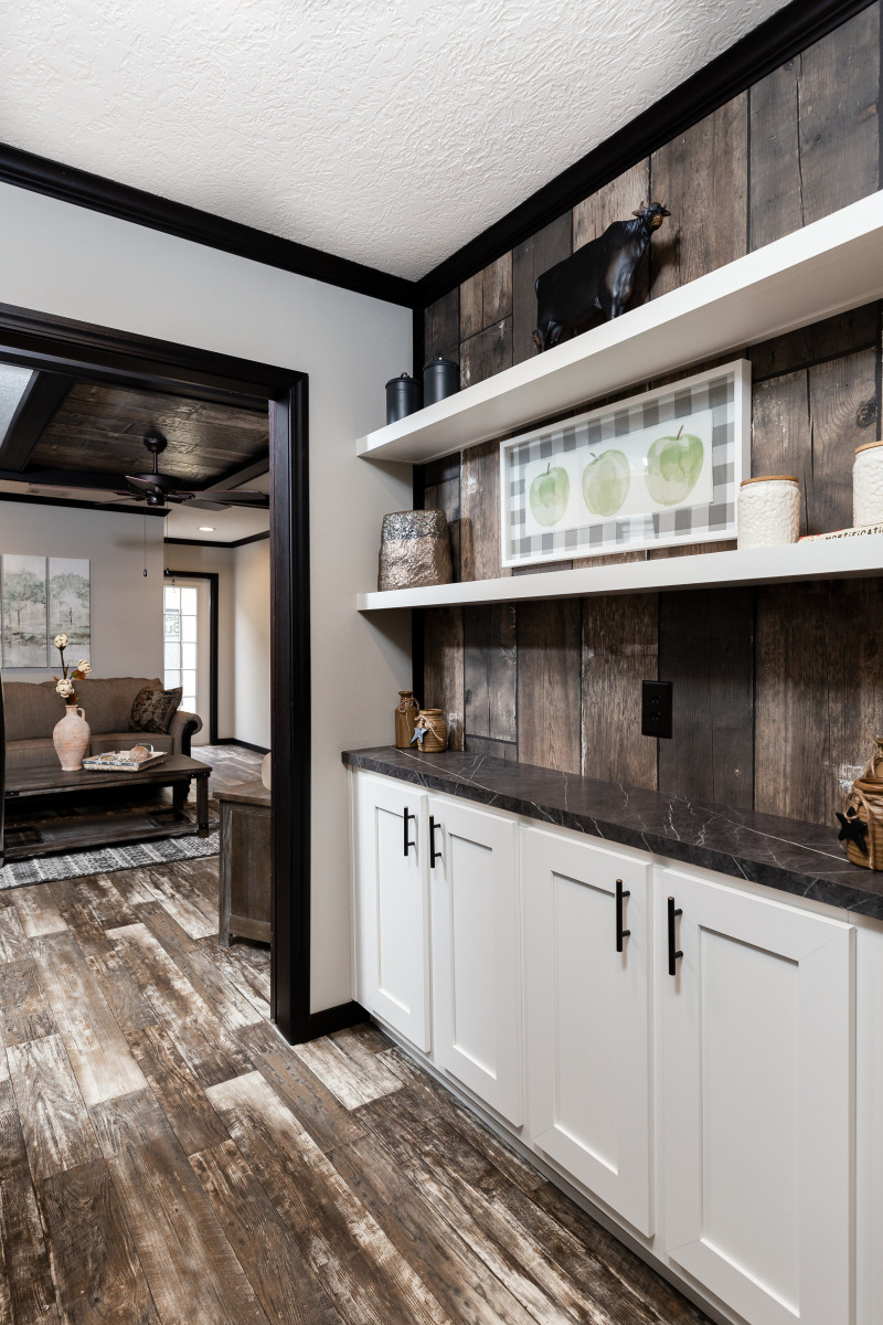 Butler’s pantry with dark counters and white cabinets in a manufactured home from Clayton.