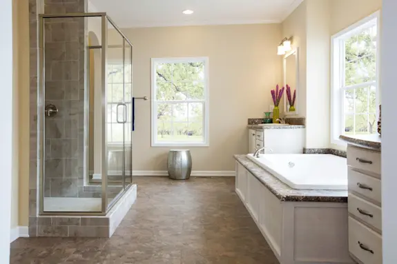 The [model name] features a primary bathroom with two separate sink vanities and a deep set shower.