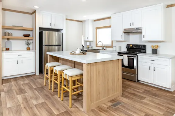 The kitchen of [model name] features a large island and open shelving.
