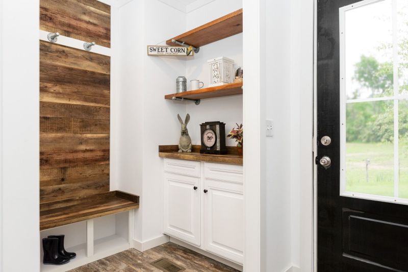 Farmhouse-style mudroom with a door to the backyard, including a hall tree with hooks and cubbies and built-in shelves with a cupboard below them.