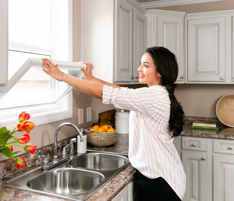 Woman cleaning the kitchen window in a manufactured home