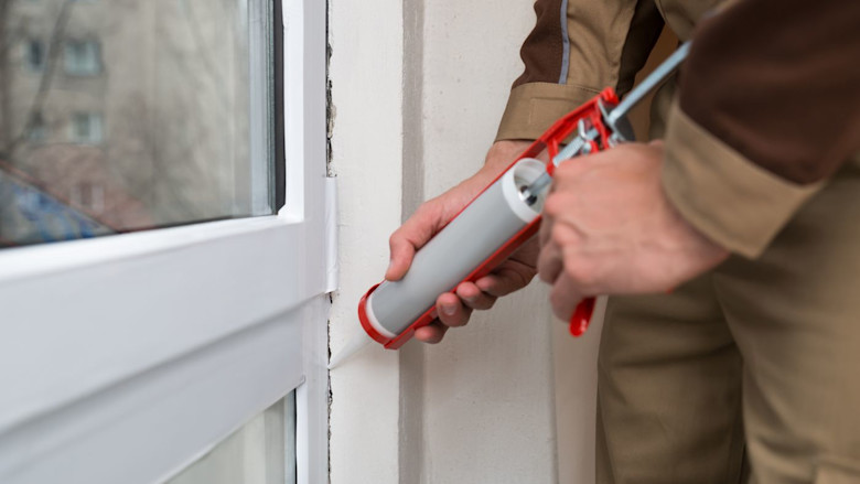 Man placing caulk on a manufactured home window.