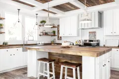 Farmhouse kitchen in a Clayton manufactured home, with white cabinets, butcher block style countertops, white walls, weathered flooring and farmhouse decor.