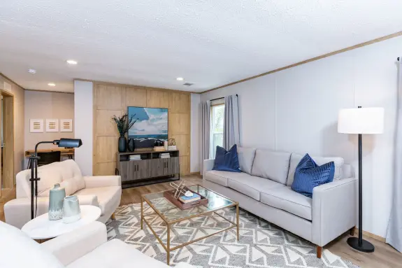 The [model name] has an open living room with a modern, grid accent wall.