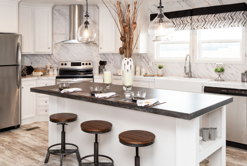 A white kitchen with a kitchen island and a marble look on the countertops and backsplash.