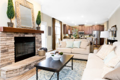 Living room of the Greystone model with fireplace feature and view into kitchen and dining areas.