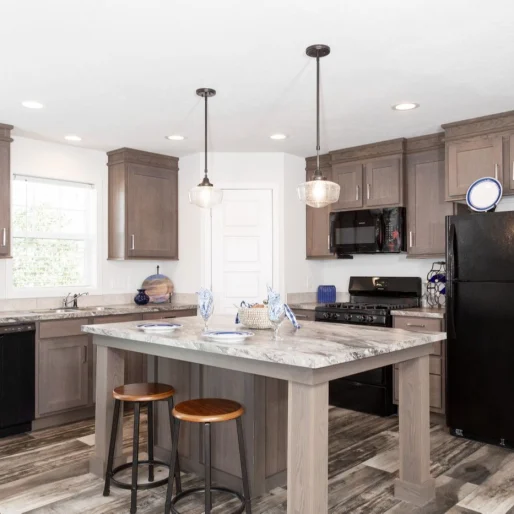 The kitchen of [model name] features a kitchen island and beautiful pendant lights.
