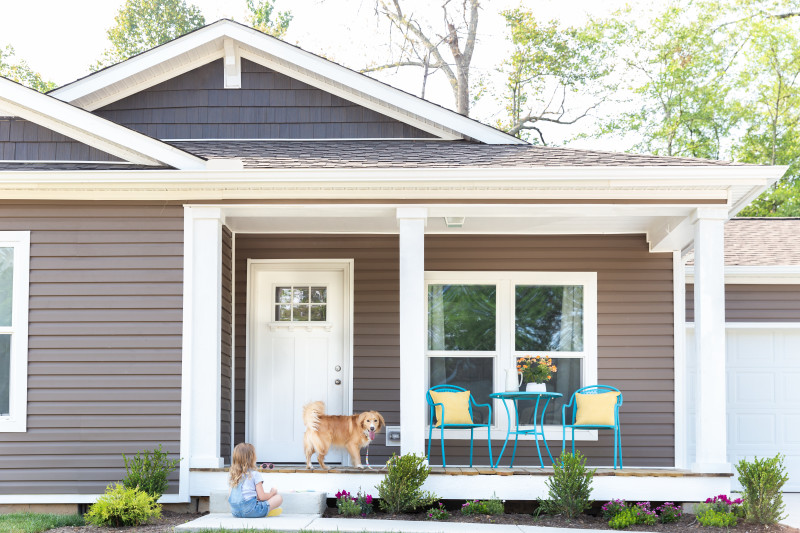 Exterior of a manufactured home with a child and dog playing.