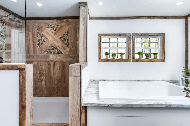 A separate rustic-style bathtub and walk-in shower featuring a wood wall in a manufactured home.