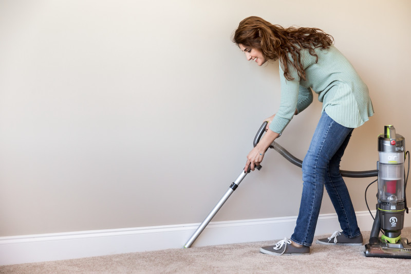 A lady vacuuming the carpet floor of her manufactured home.