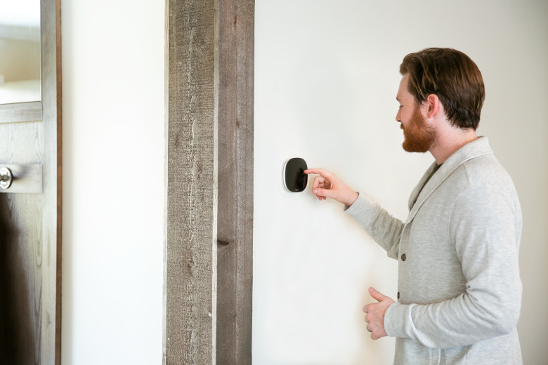 Man touching an ecobee thermostat on the wall of a manufactured home.