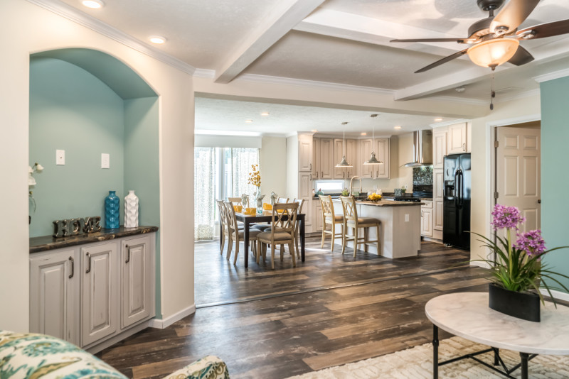 Living room with an entertainment center and an open area leading into the kitchen/dining room area.