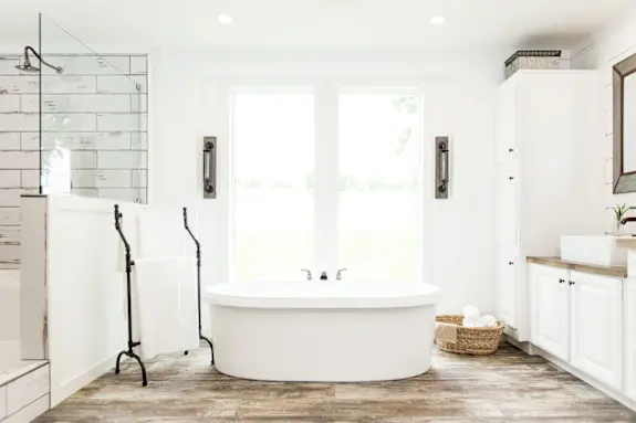 The primary bathroom of [model name] features built-in linen cabinets and a soaker tub.