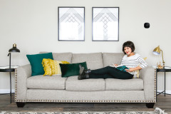 Woman sitting on a couch in a manufactured home living room with an ecobee thermostat on the wall.