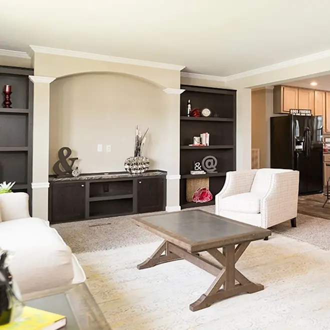 Open shelving, white crown molding and plush carpet in the Versailles create a fantastic view of this spacious living room.