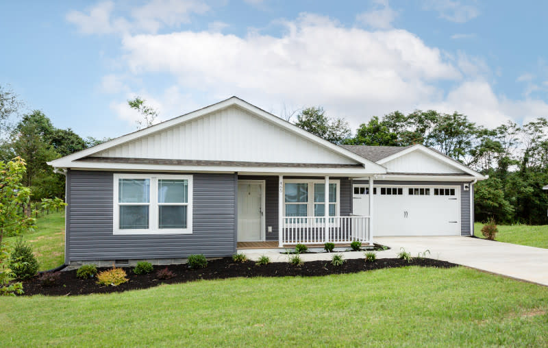 Exterior of a CrossMod home with blue-gray and white siding, a small front porch and a garage with a driveway.