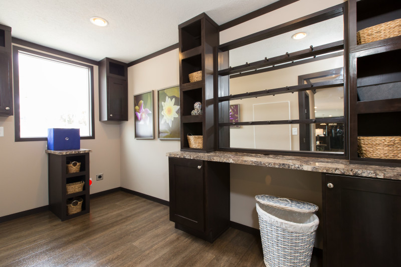 Dark stained cabinetry in a manufactured home utility room with a large built-in desk.