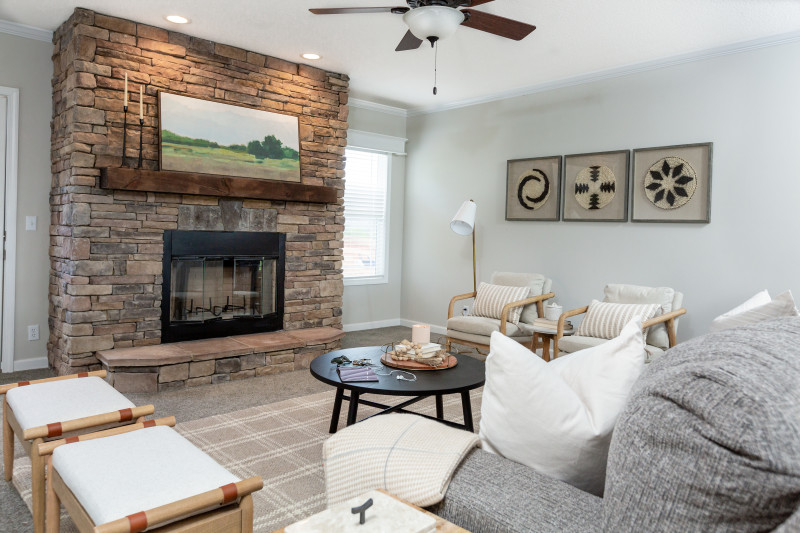  There's a stone to ceiling fireplace with windows on either side. There's gray and white furniture also in view.