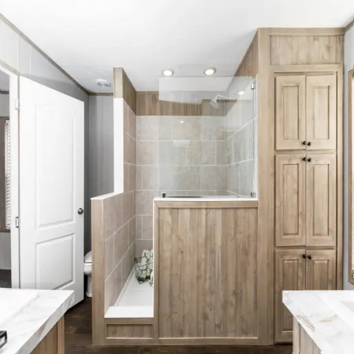 The bathroom in [model name] features a walk-in shower with a rainfall showerhead and a built-in linen closet.