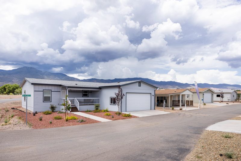 Manufactured home in a community with garages and small driveways.