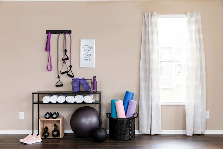 Manufactured home gym with towels, bright colored weights, and inspirational sign on the wall.