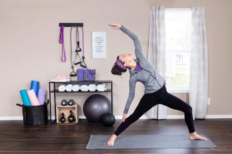 Woman doing yoga in her manufactured home home gym featuring bright colored equipment in the background.
