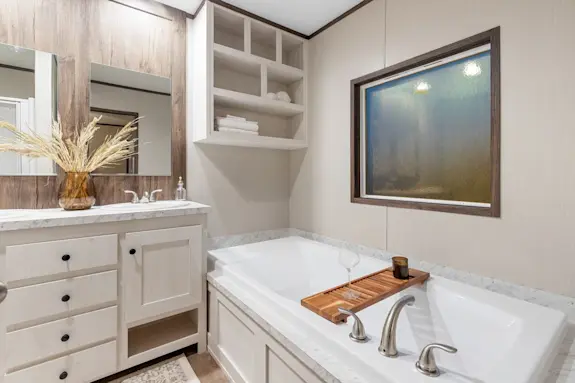 The [model name] features a primary bathroom with a drop-in tub and built-in cubbies.